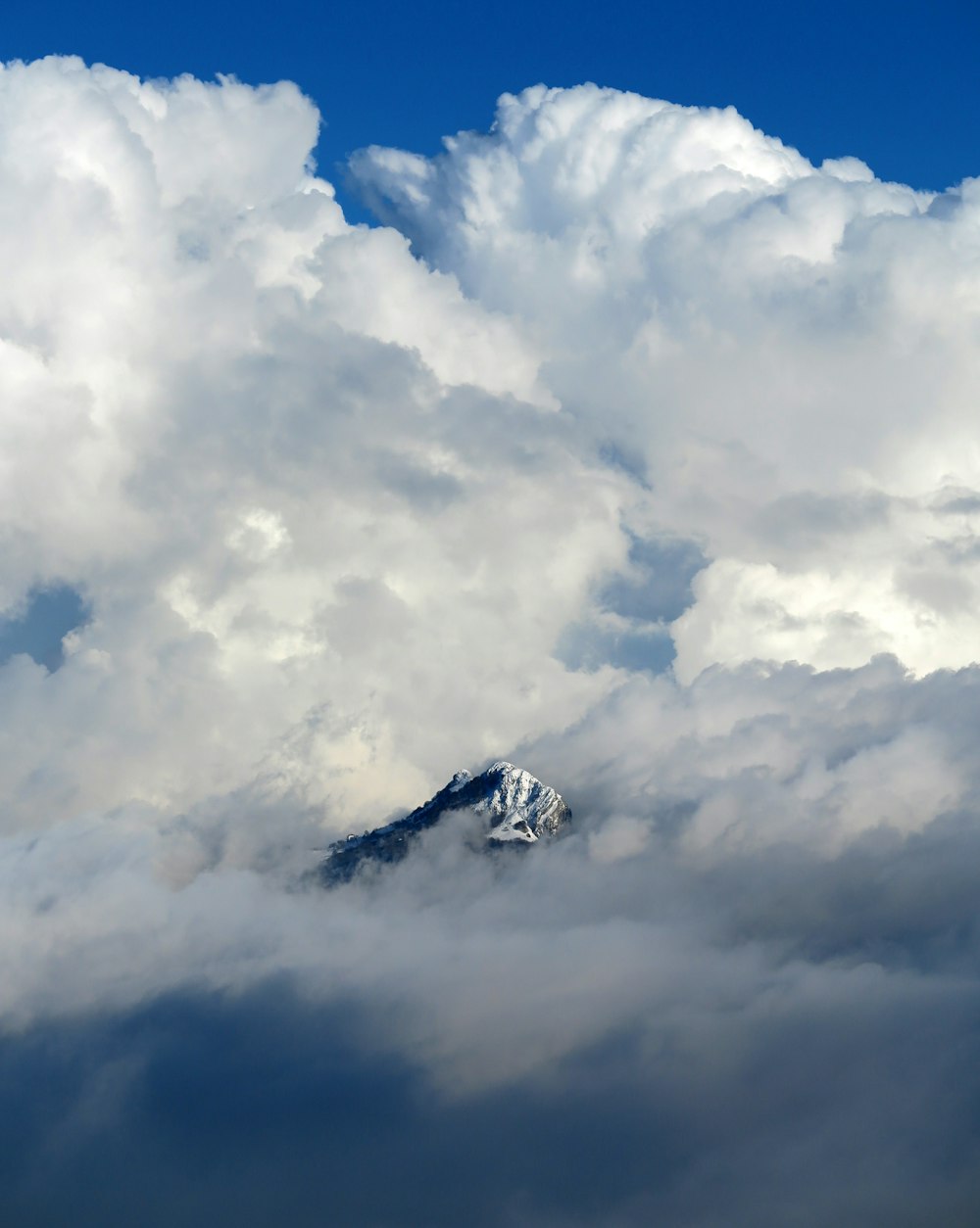 a mountain in the middle of a cloud filled sky