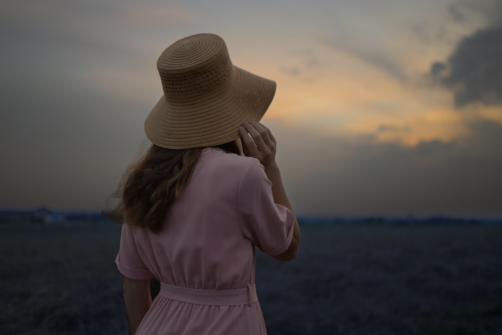 a woman in a hat standing in a field