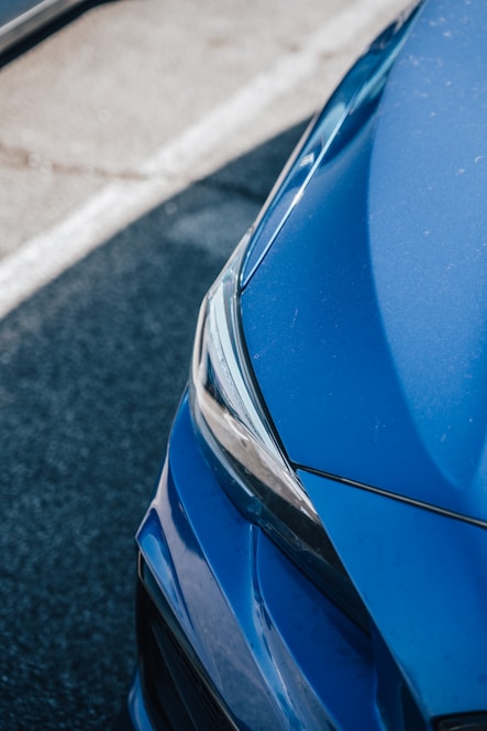 A focused buyer examining a used car at an auction lot under bright daylight