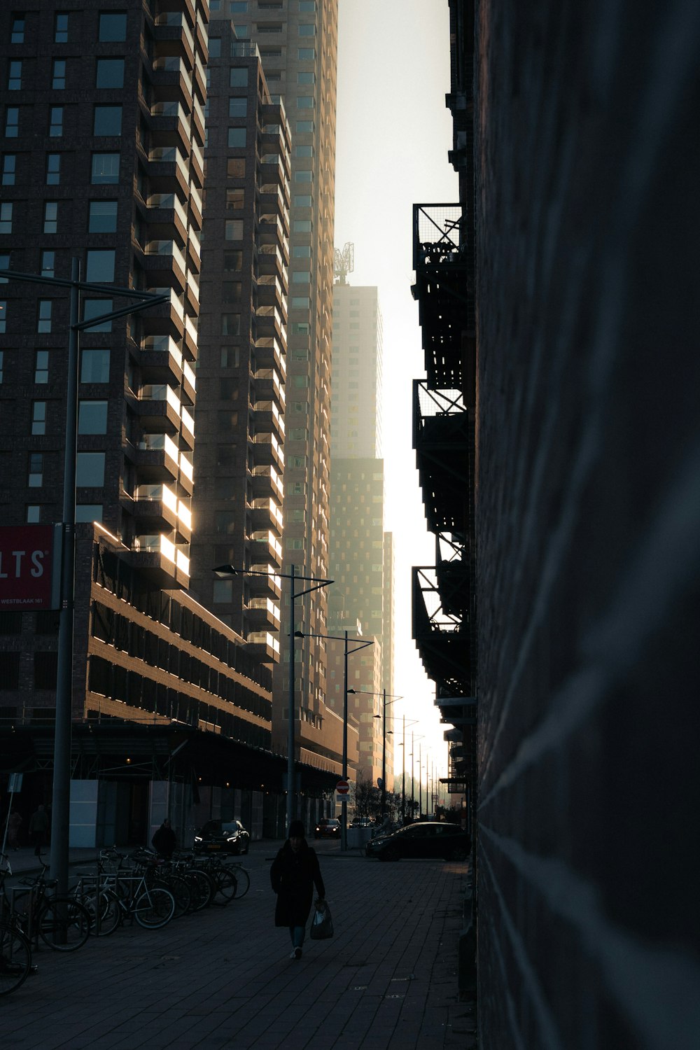 a person walking down a street next to tall buildings