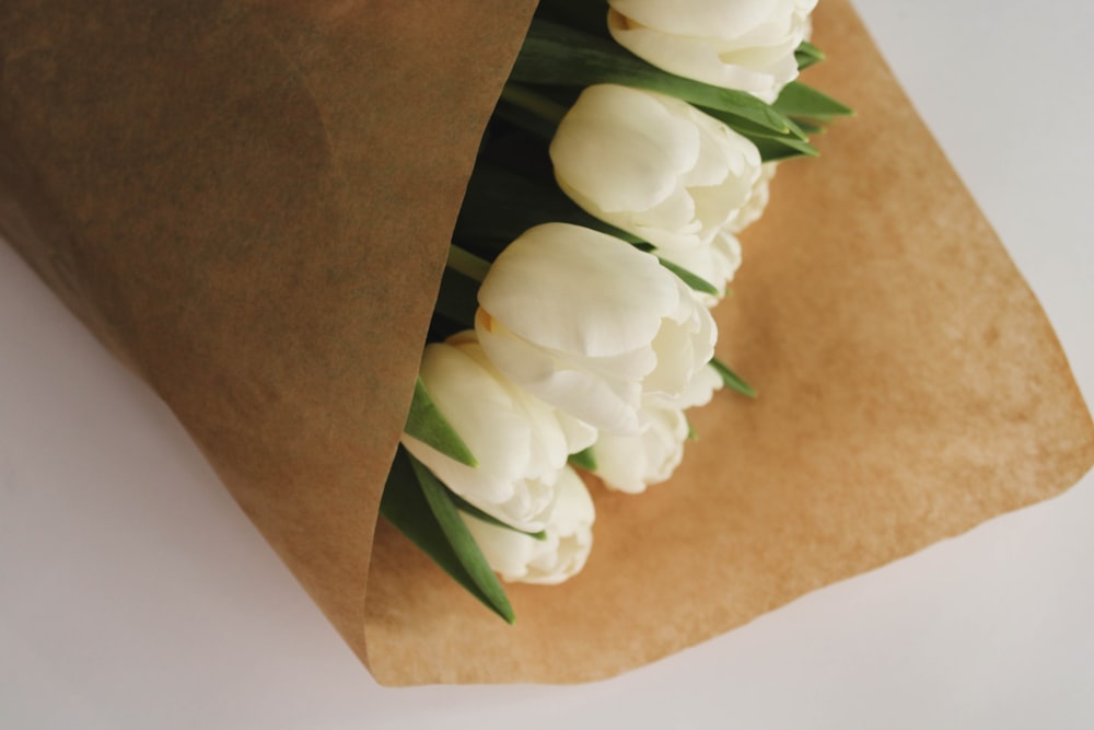 a bunch of white flowers sitting inside of a brown paper bag