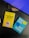 Two books placed on a desk with part of a keyboard visible. One book has a yellow cover titled 'A Thousand Brains' by Jeff Hawkins, featuring an illustration of a human head with puzzle pieces. The other book has a turquoise cover titled 'Say Less, Get More' by Fotini Iconomopoulos, with speech bubbles on the cover. The setting appears to be a workspace.