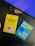 Two books placed on a desk with part of a keyboard visible. One book has a yellow cover titled 'A Thousand Brains' by Jeff Hawkins, featuring an illustration of a human head with puzzle pieces. The other book has a turquoise cover titled 'Say Less, Get More' by Fotini Iconomopoulos, with speech bubbles on the cover. The setting appears to be a workspace.