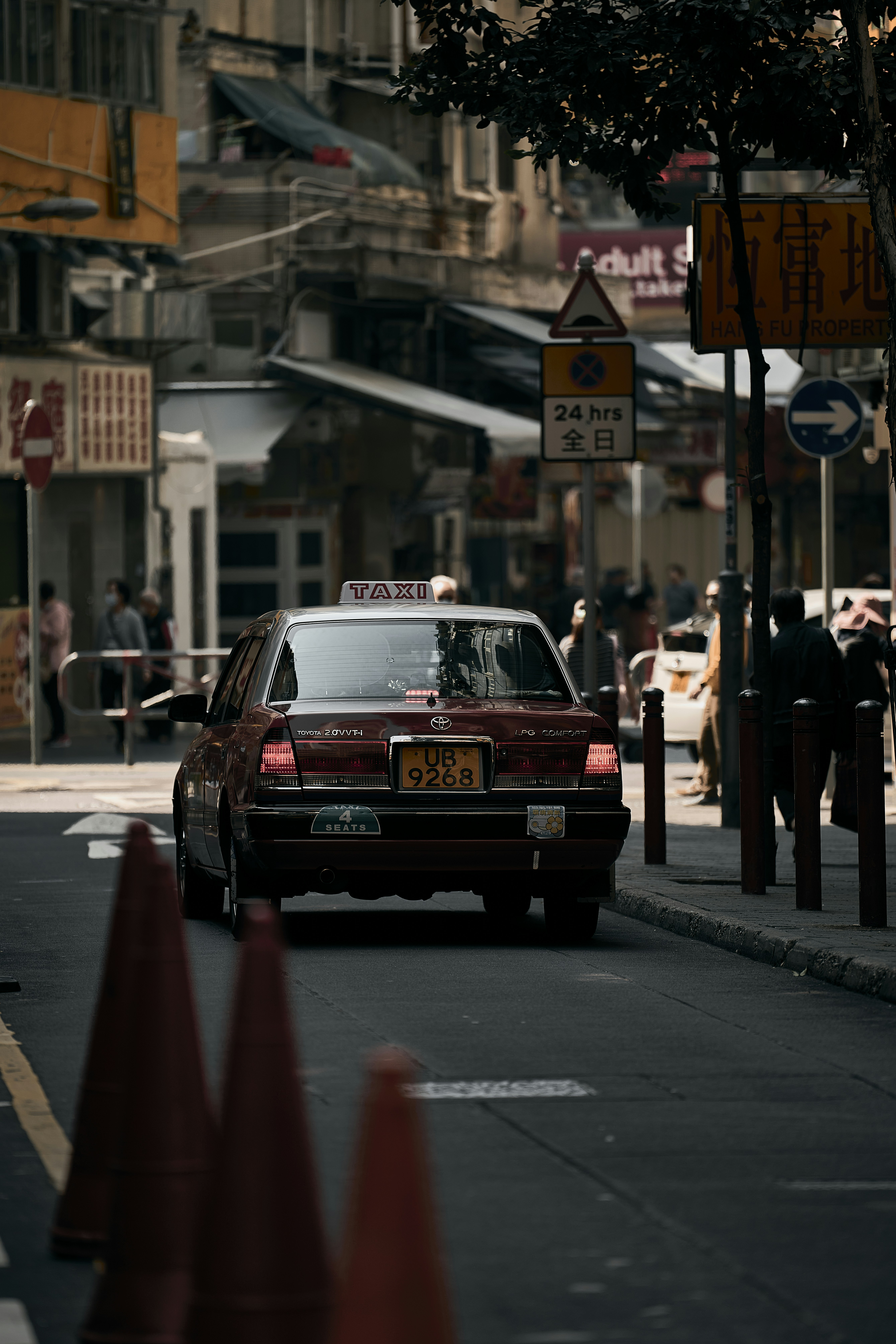 a red taxi cab driving down a street next to traffic cones