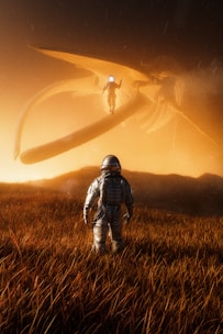 A lone astronaut stands in a field of tall, golden grass beneath a large, mysterious alien creature hovering above. The scene is bathed in warm, orange light, creating an atmospheric and surreal environment.