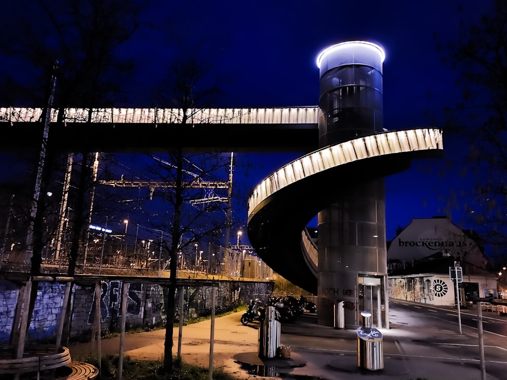 a bridge over a street at night with a building in the background