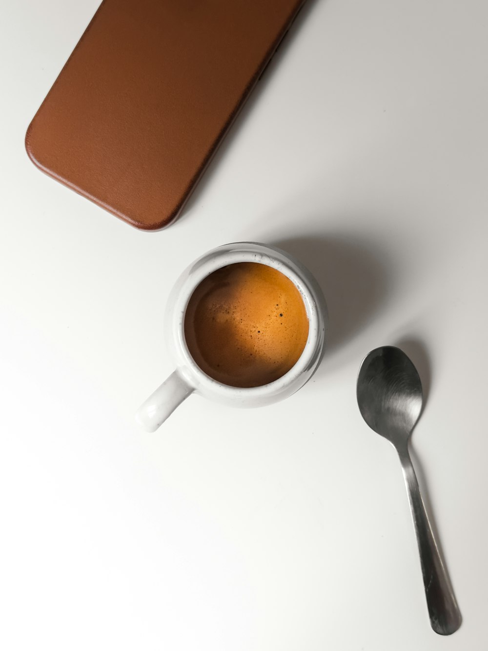 a cup of coffee next to a spoon
