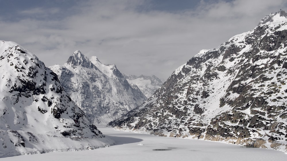 a snow covered mountain range with a lake in the foreground