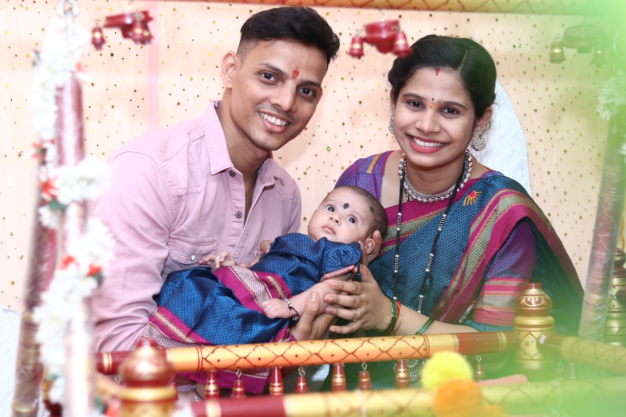 A joyful family dressed in vibrant Kanchipuram silk sarees and traditional attire, standing in front of a temple gopuram backdrop with subtle kolam patterns.