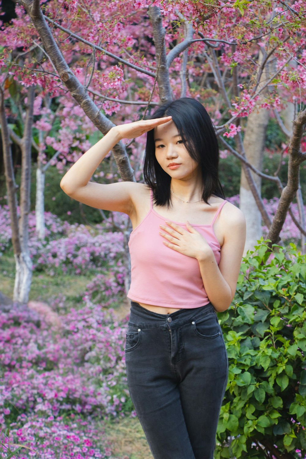 Une femme debout devant un arbre avec des fleurs roses