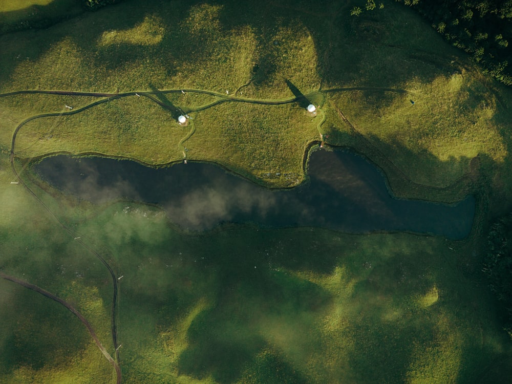 an aerial view of a lake surrounded by green grass