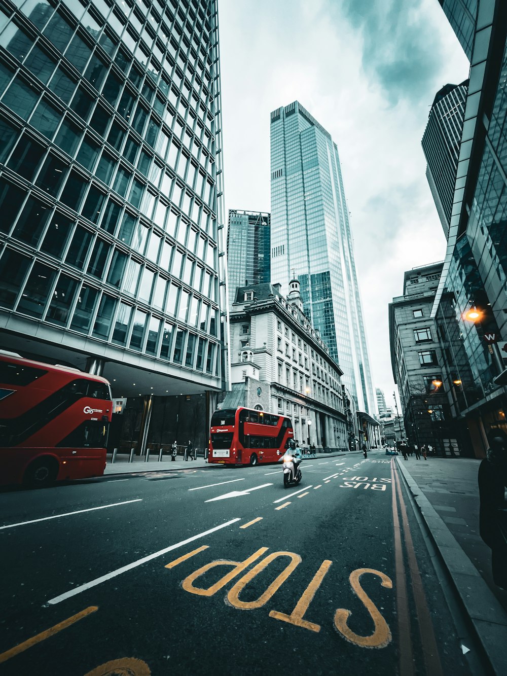 a red bus driving down a street next to tall buildings