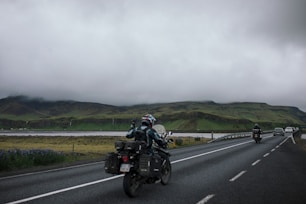 a couple of people riding motorcycles down a road