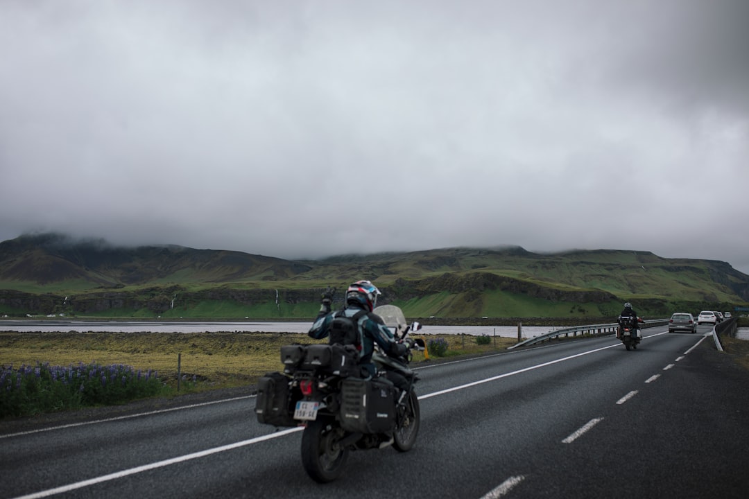 a couple of people riding motorcycles down a road,