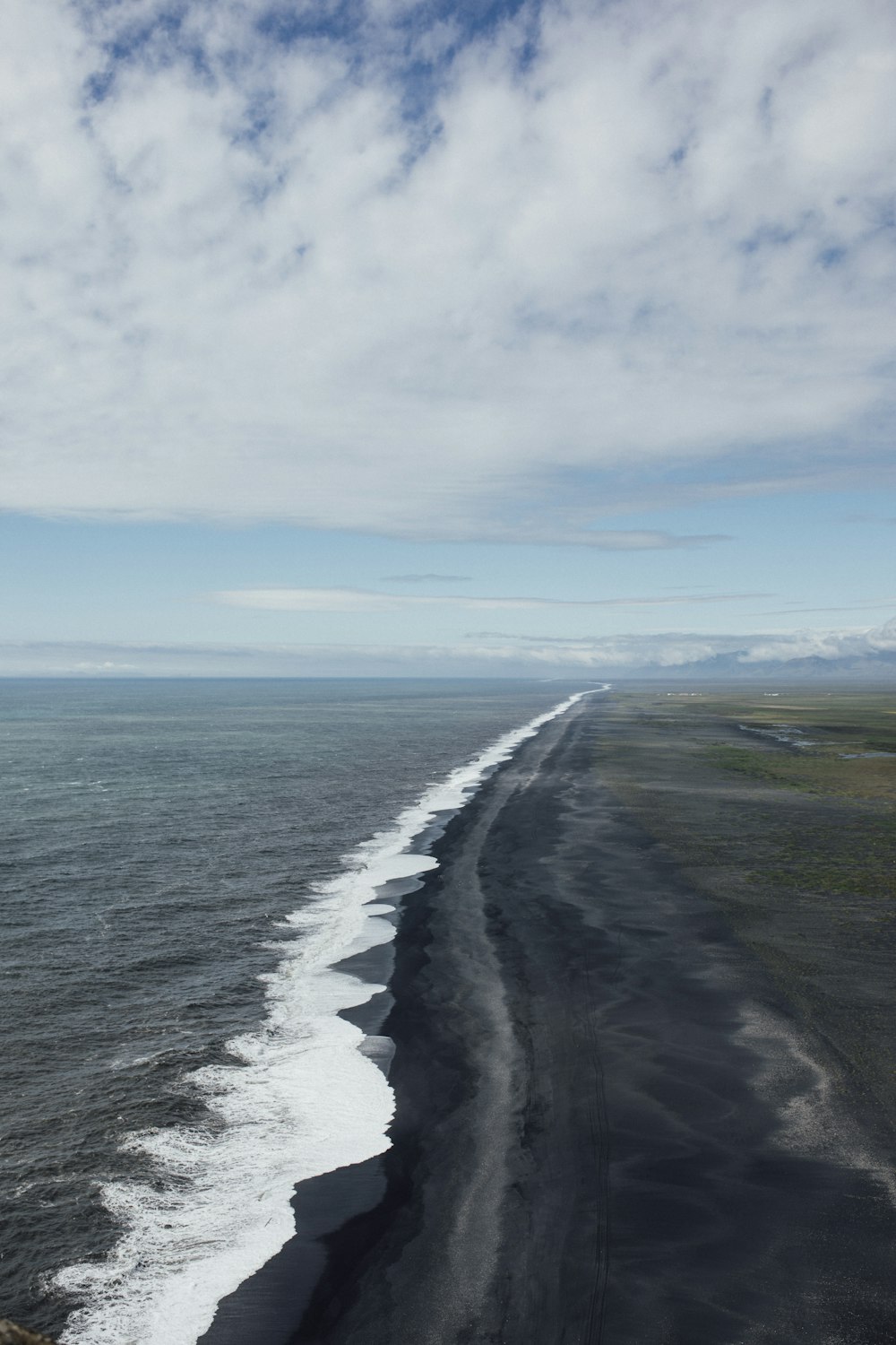 a long stretch of black sand beach next to the ocean
