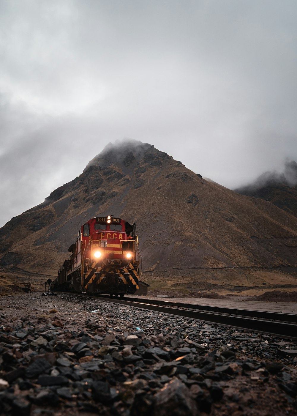 a train traveling down train tracks next to a mountain