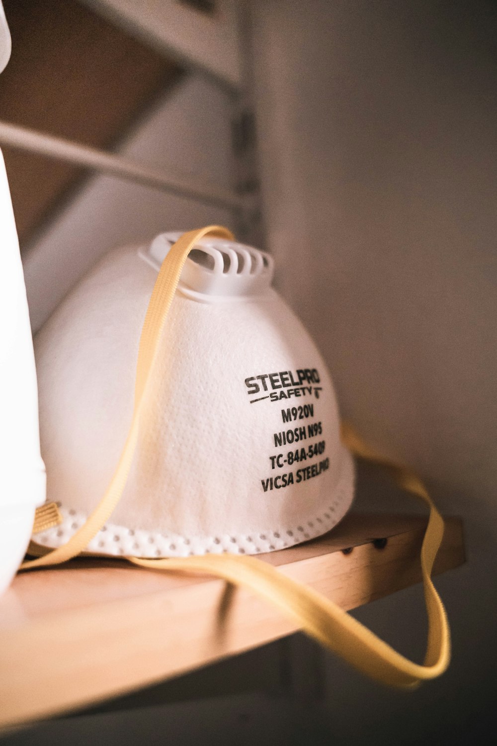 a white mask sitting on top of a wooden shelf