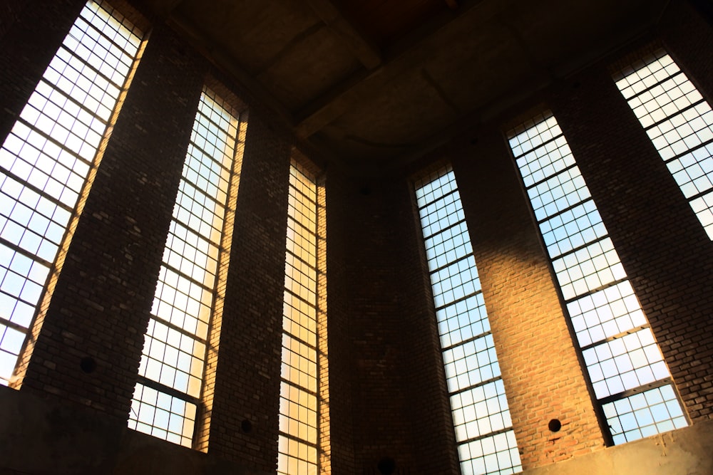 três janelas em um edifício de tijolos com a luz do sol vindo através deles