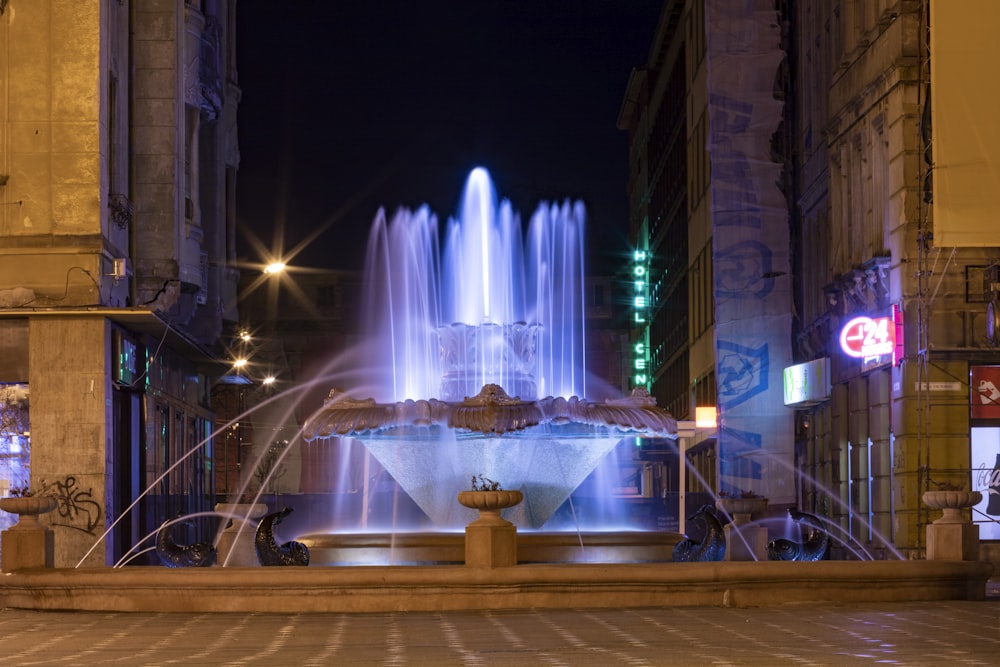 a fountain in the middle of a city at night