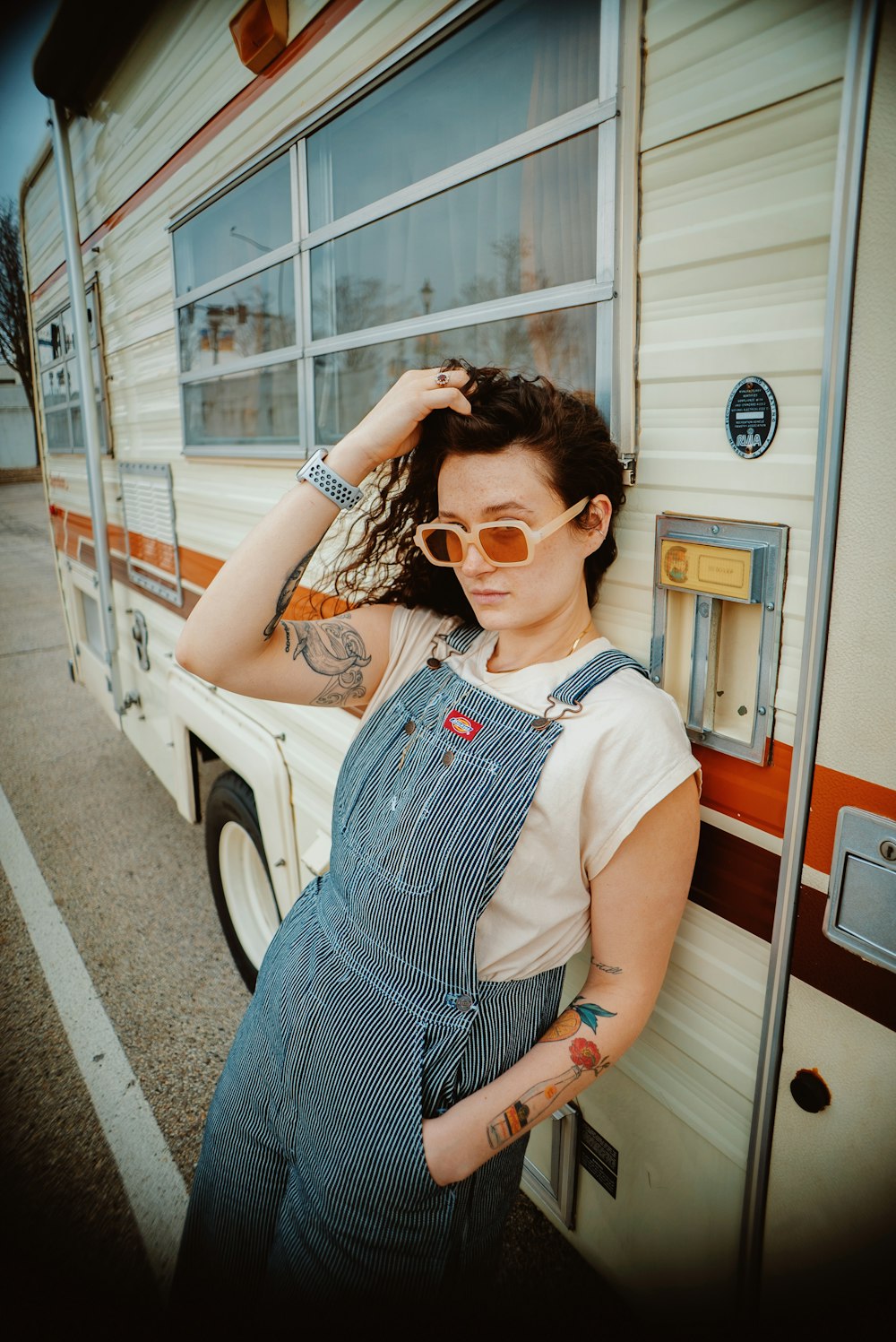 a woman in overalls leaning against a trailer