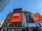A cityscape image featuring the entrance of Madison Square Garden with large digital advertisements on the building facade. The advertisements promote a partnership with the New York Knicks and DoorDash, featuring bold typography and vibrant orange backgrounds. The iconic Empire State Building is visible in the background, and the clear blue sky adds to the urban setting. The signage for Pennsylvania Station is prominently displayed below.