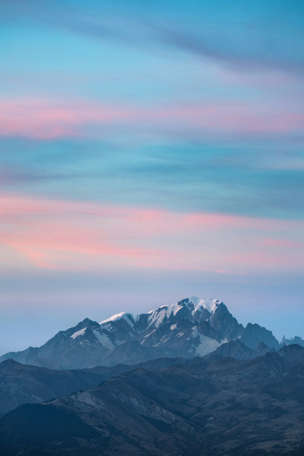 a mountain range with a pink and blue sky in the background