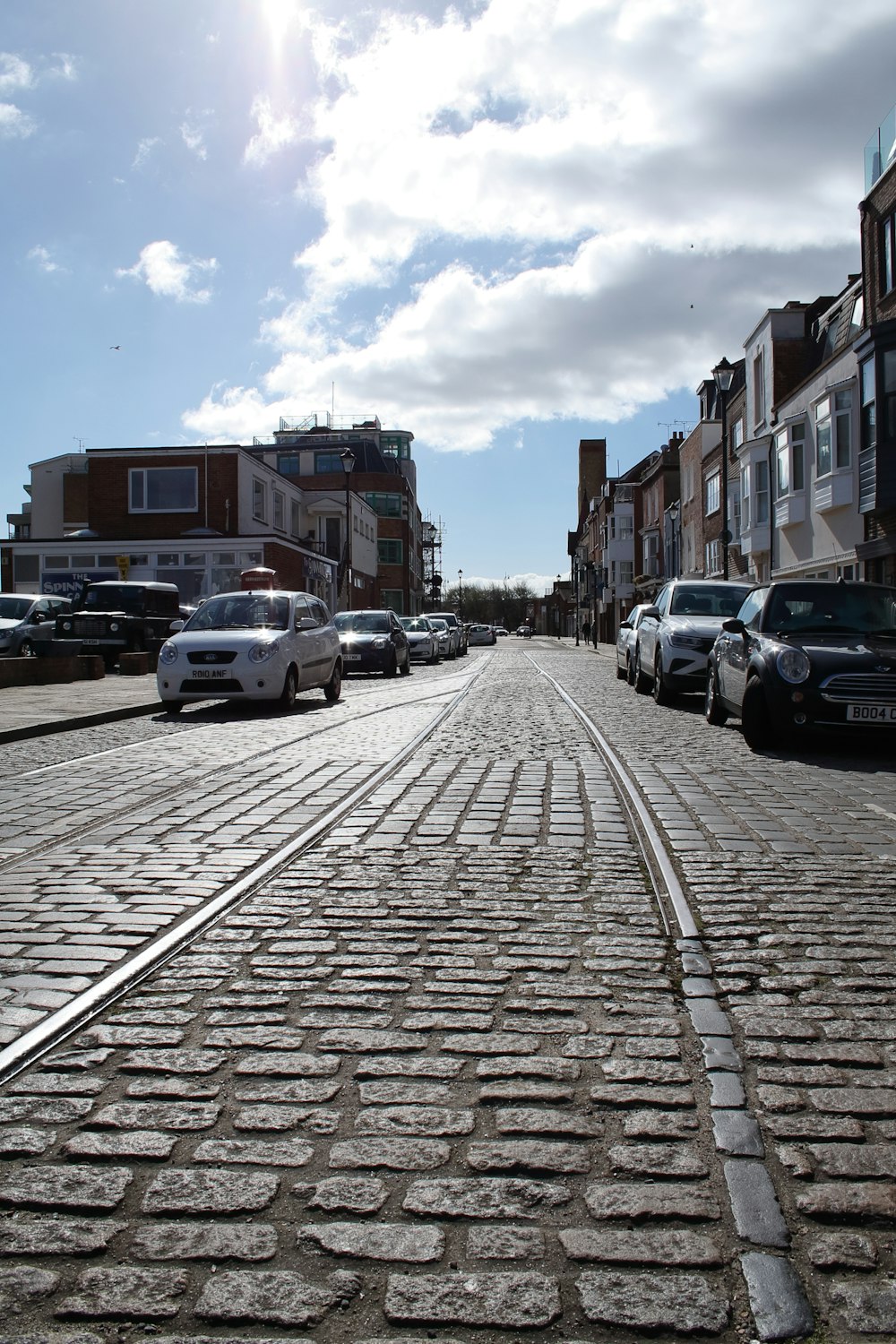 a cobblestone street with cars parked on both sides