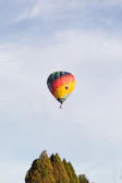 A colorful hot air balloon floating peacefully above a patchwork of green fields.