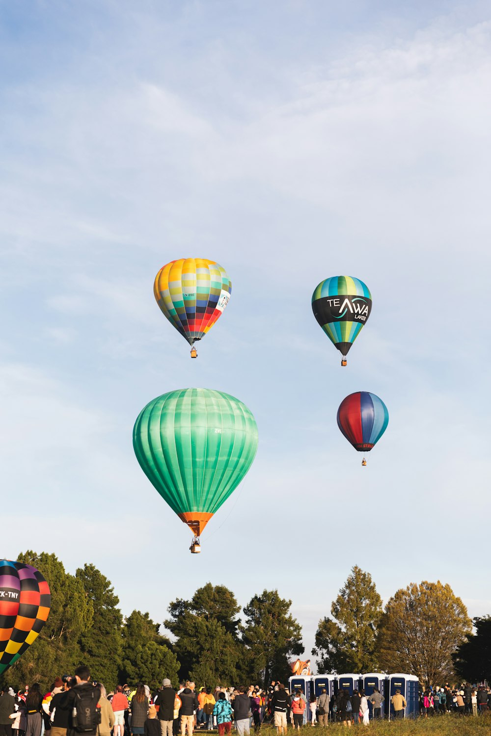 um grupo de pessoas observando balões de ar quente no céu
