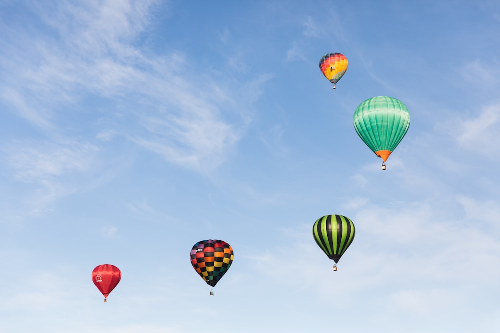 a group of hot air balloons flying through a blue sky