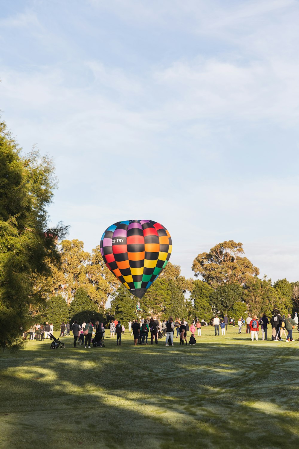 a group of people standing around a colorful hot air balloon