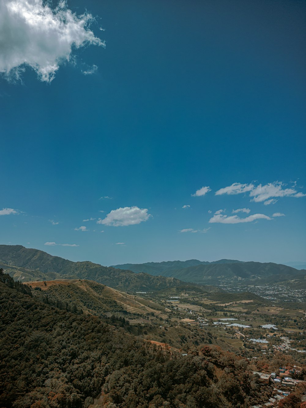 a scenic view of a valley and mountains under a blue sky