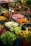 A vibrant array of flowers in a market setting, featuring bouquets of various colors such as red, pink, white, orange, and green. Each bouquet is placed in a bucket and labeled with price tags in Euros, indicating a busy and colorful floral stall.