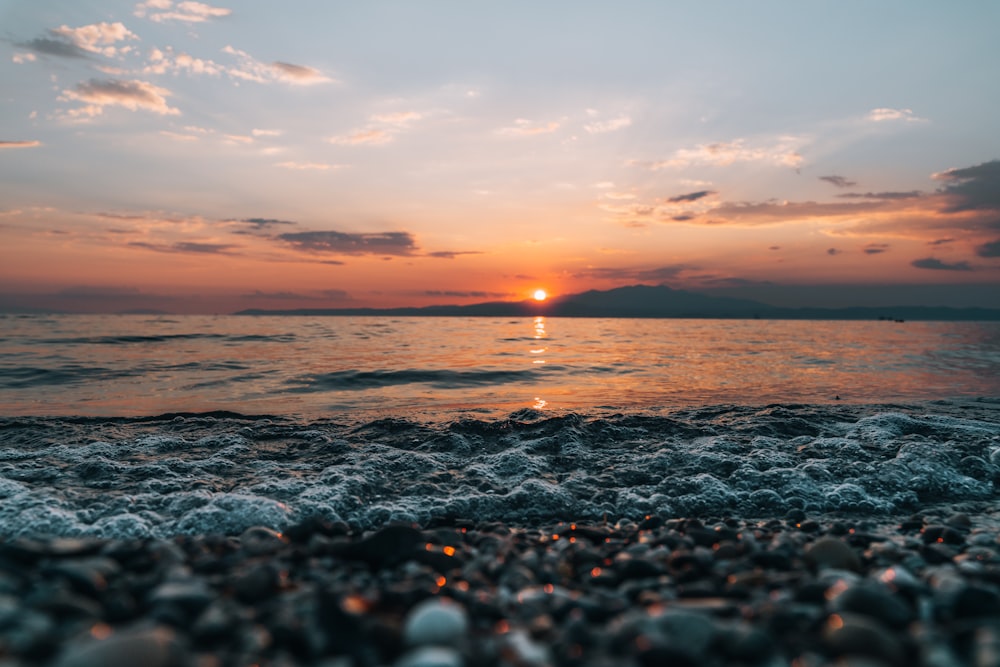 the sun is setting over the ocean on the beach