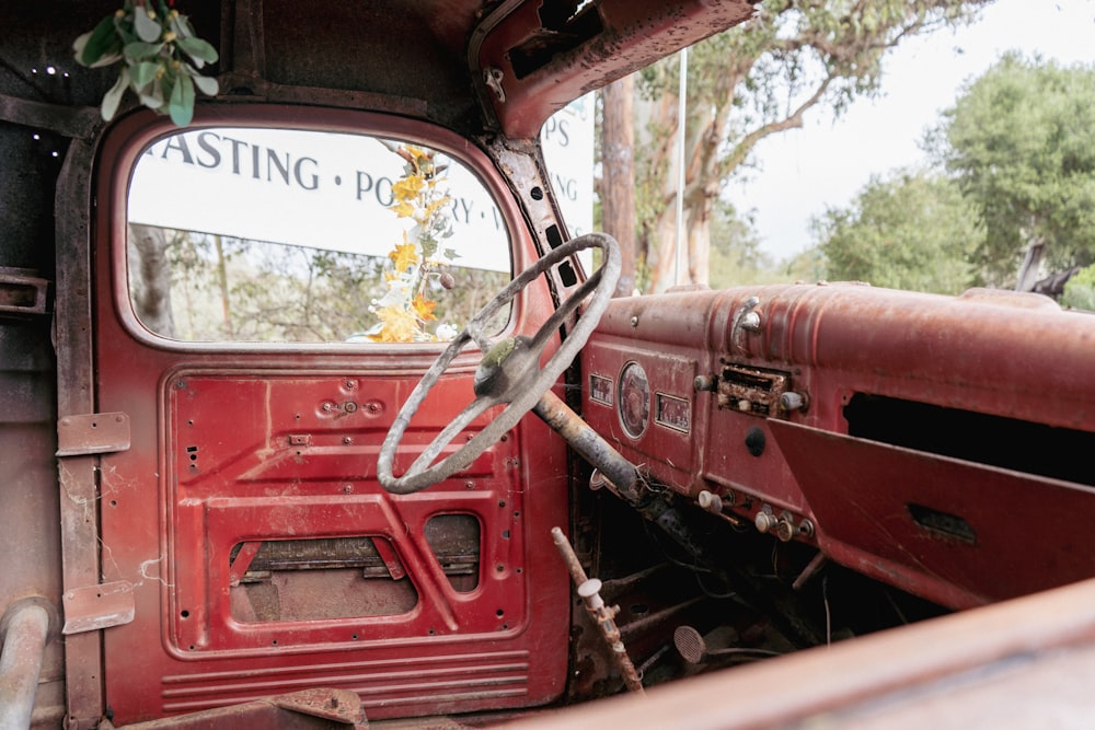 the interior of an old red truck with a steering wheel
