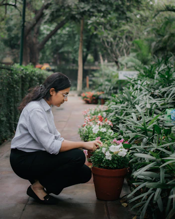 A gardener carefully cleaning and arranging flowers in a serene garden setting.
