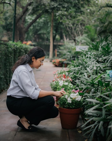 A gardener tending to a vibrant residential garden with flowers and greenery.