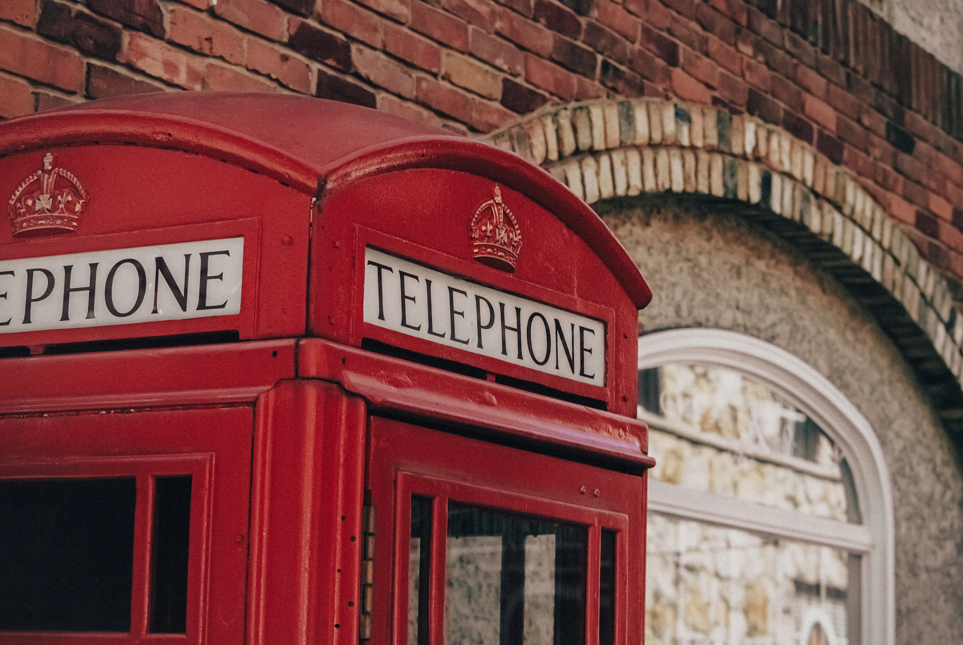 a red telephone booth in front of a brick building