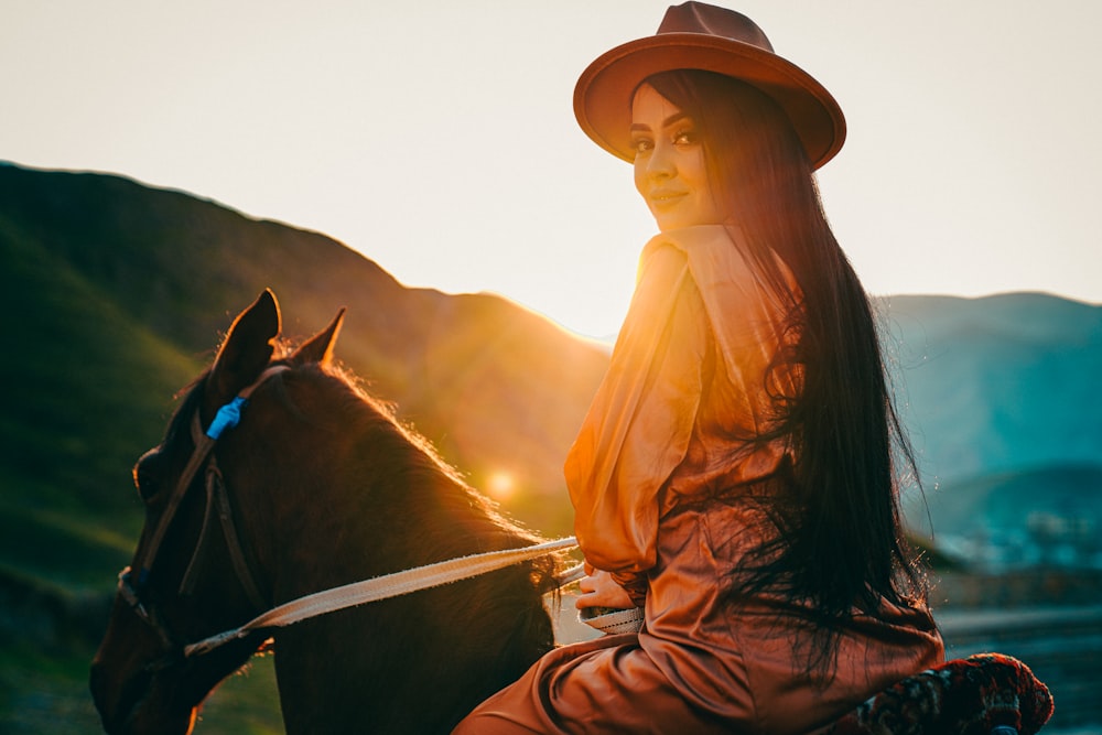 Une femme assise sur un cheval au coucher du soleil