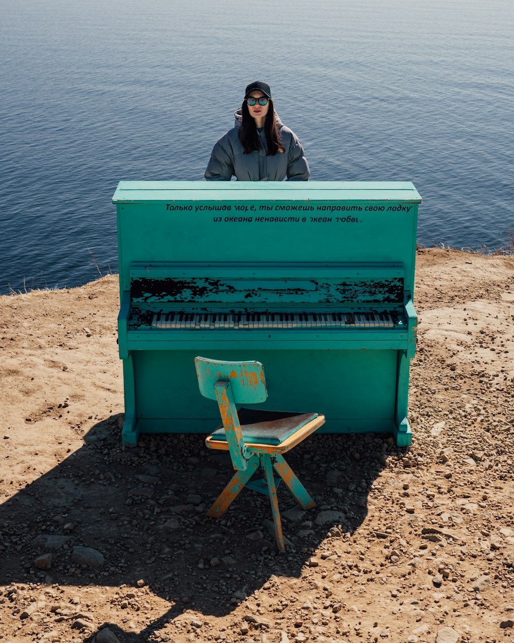 a woman sitting at a piano on a beach