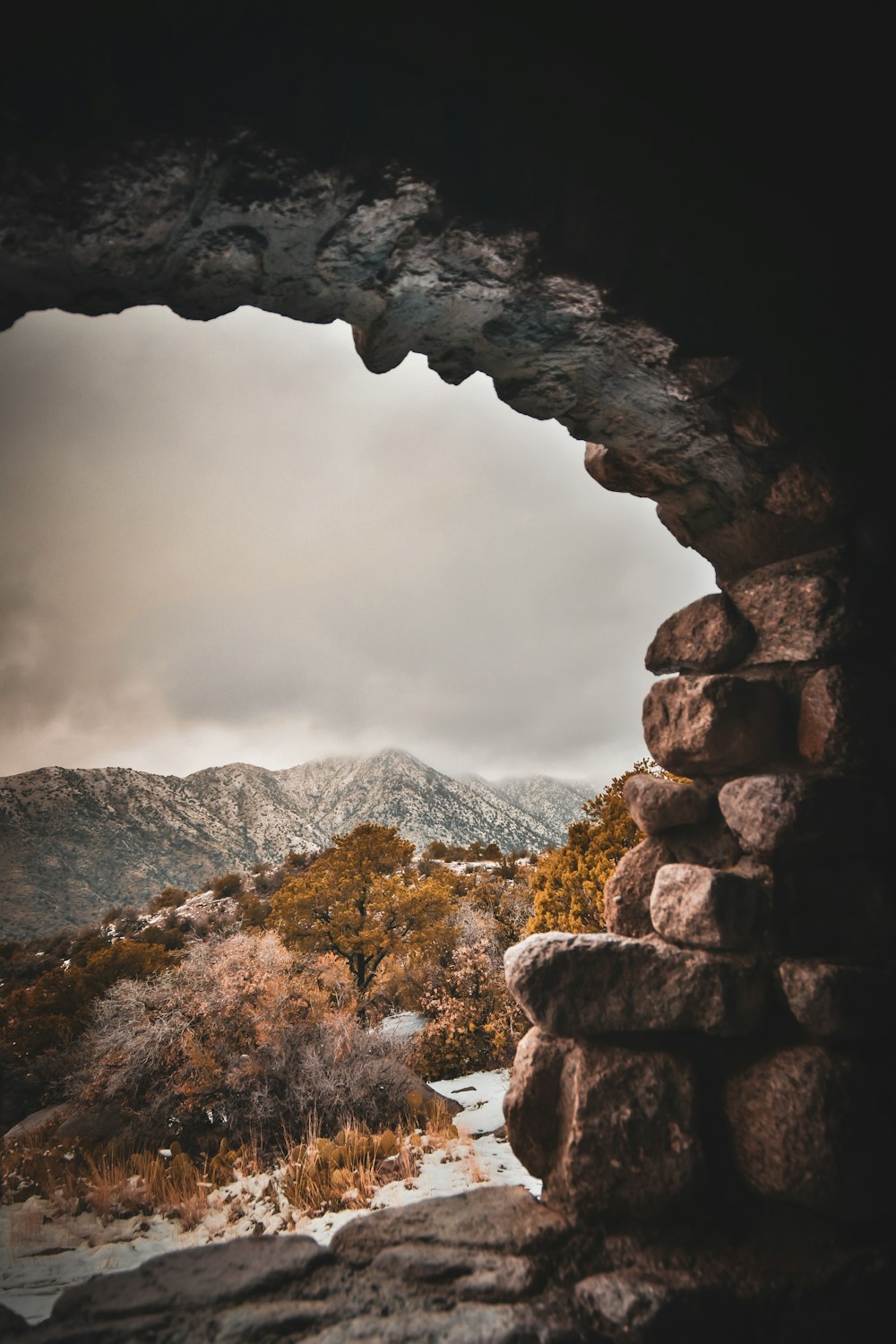 a view of mountains through a stone window