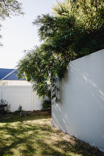 A beautifully landscaped backyard in Ada featuring a stone patio and lush greenery under a clear blue sky.