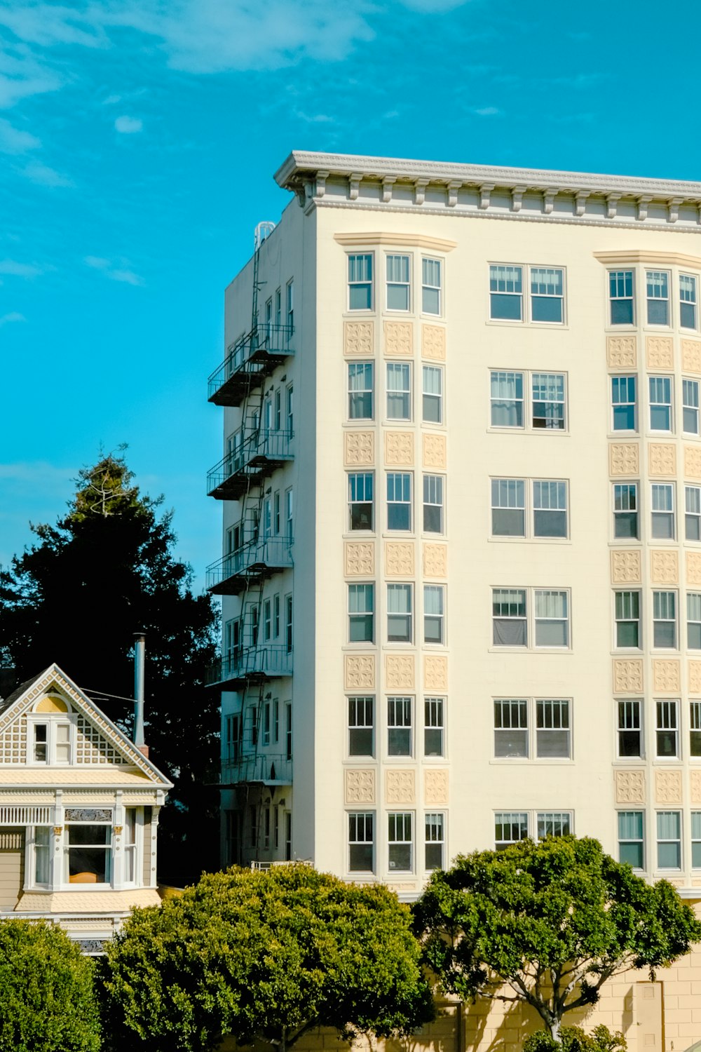 a tall white building sitting next to a lush green park