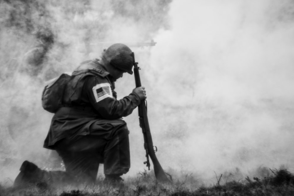 um homem segurando um rifle na frente de uma nuvem de fumaça