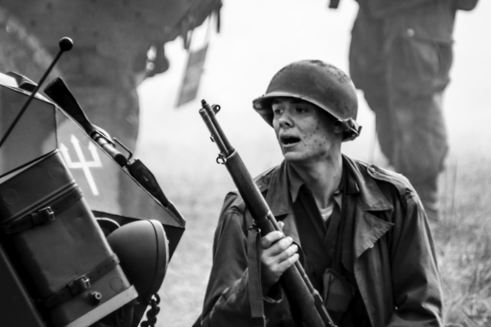 a man holding a rifle next to a motorcycle