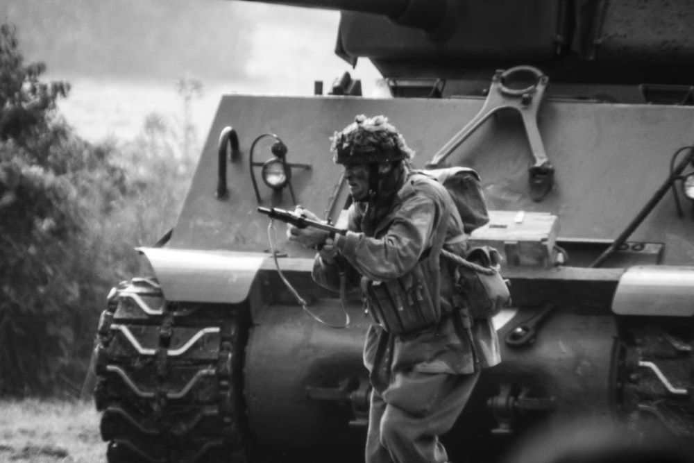 um homem com uma arma em pé na frente de um tanque