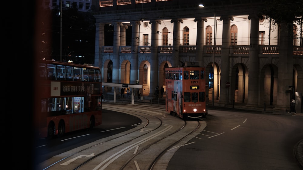 a double decker bus driving down a street at night