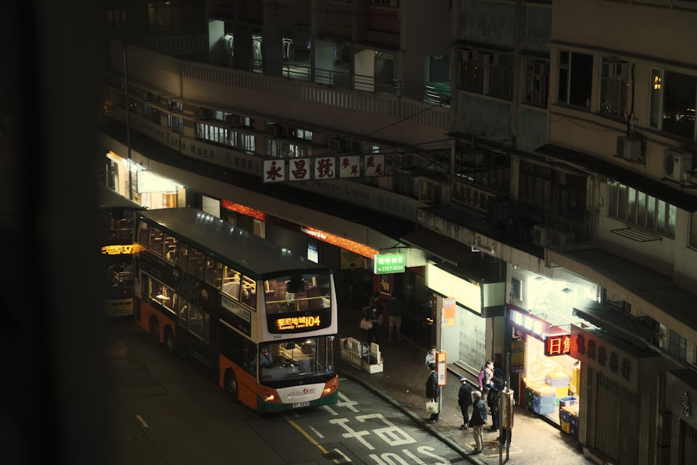 a double decker bus driving down a street at night