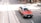 A red and white taxi is driving on a city street with tram tracks visible. The street appears bustling, with a pedestrian in the background and other vehicles parked nearby. The sunlight casts shadows on the street, creating a vibrant urban scene.