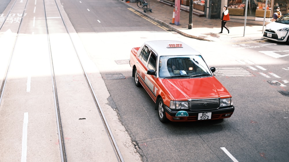 a small red car is parked on the side of the road